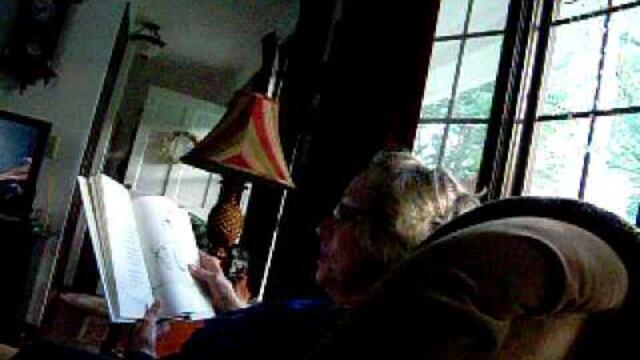 Grandma laughing hysterically while reading a funny book.