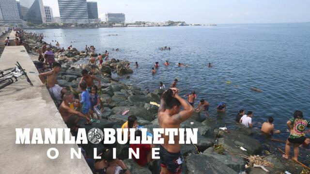 People plunge into the cool water of Manila Bay in Pasay City