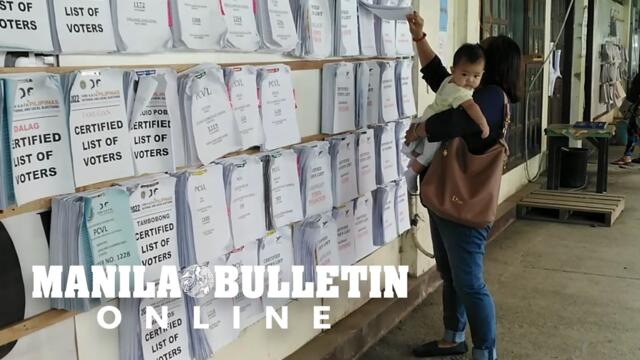 Voters in Davao City check their precinct numbers posted by the Comelec a week before the elections
