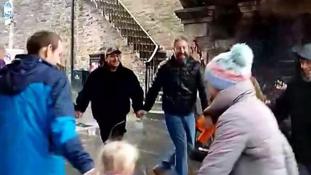 People dancing under Magazine Gate on a rainy day in Derry