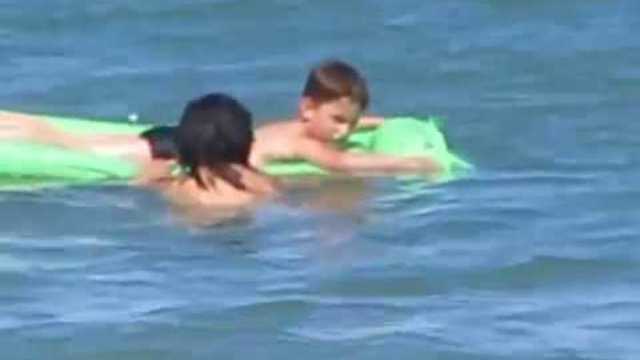 Kids swimming in the sand at the beach in high sea with mum